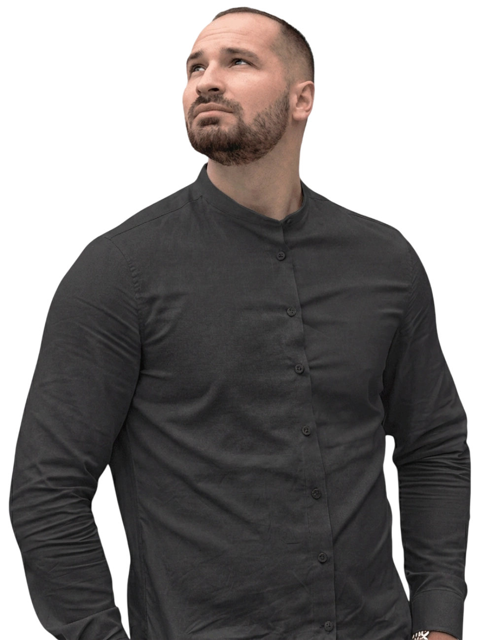 Bearded man in a buttoned dark gray shirt looking upward with a thoughtful expression.